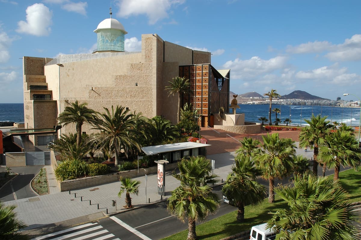 El Auditorio Alfredo Kraus junto a la Playa de las Canteras, con su torre cilíndrica y La Isleta al fondo